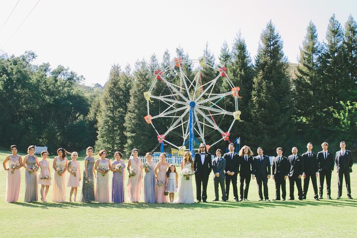Marisa and Kyle stood in a line with their wedding party outside at Calamigos Ranch in Malibu, California, with the Ferris wheel on the property right behind them. The bridesmaids wore a variety of dresses in different styles, colors and lengths, while the groomsmen matched Kyle and wore black Tom Ford tuxedos paired with bow ties.