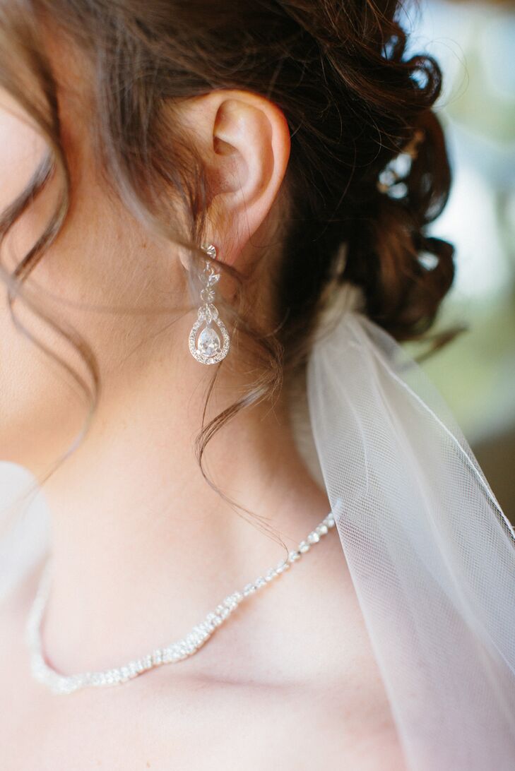 Kellie wore a dangling pair of teardrop earrings accented with crystals and an elegant thin silver necklace. The two pieces of jewelry went with the crystal accents that were seen throughout her wedding dress silhouette.