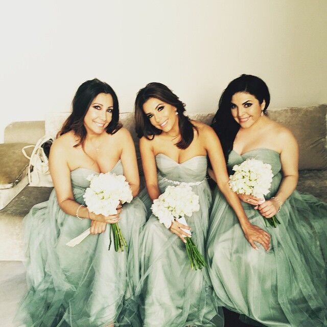 Eva Longoria and other bridesmaids sit on a couch and smile for the camera. 