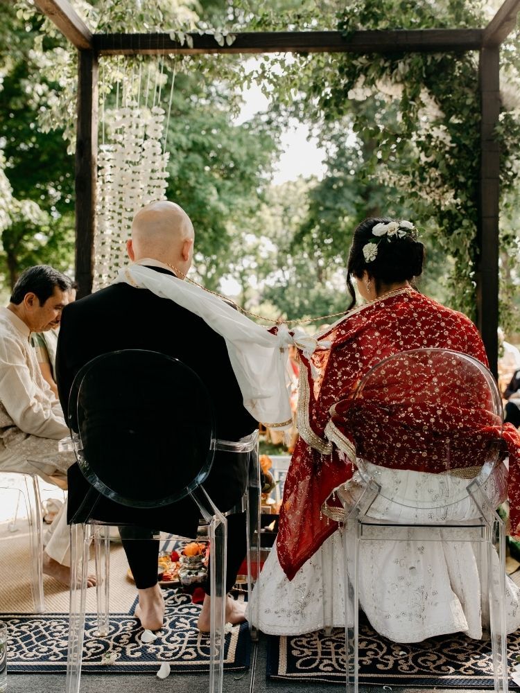 bride and groom tying shawl and scarf together during Hindu wedding ceremony