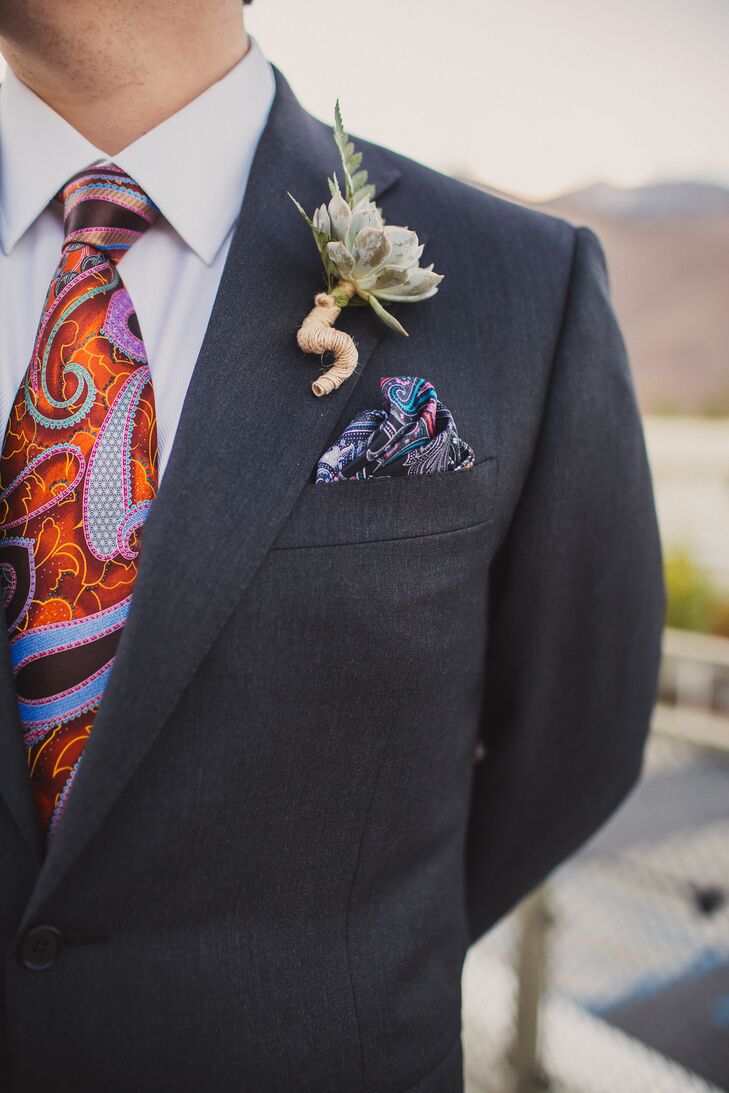 Matt wore a charcoal suit designed by Canali, accented with a purple and orange paisley tie and a matching pocket square tucked into his jacket. A green succulent with a yarn wrap was pinned to his jacket lapel, going along with the rustic-theme of the wedding day.