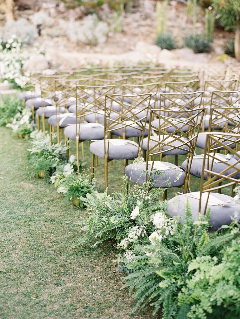 outdoor wedding ceremony aisle with gold chameleon chairs and fern aisle markers