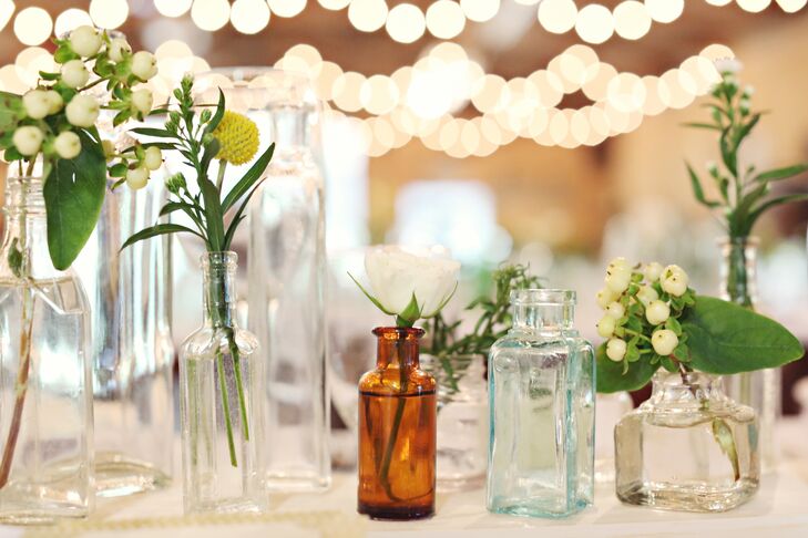 Over a few months, I collected about a thousand (yes, a thousand!) antique glass bottles in varying sizes and colors, says Aimee. We filled them with mini garden roses, hypericum berries and craspedia--I wanted the bottles themselves to be featured, so we chose simple, small flowers to fill them.