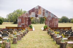 Tin Barn-Shaped Wedding Backdrop with Tree Stumps and Wildflowers Lining Aisle