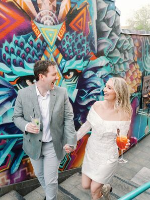 Bride in Mini Dress and Groom in Gray Suit Sip Cocktails at Colorful Rehearsal Dinner