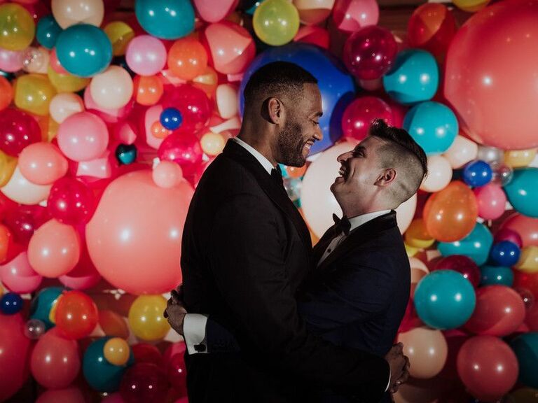 Couple sharing embrace in front of balloon wall