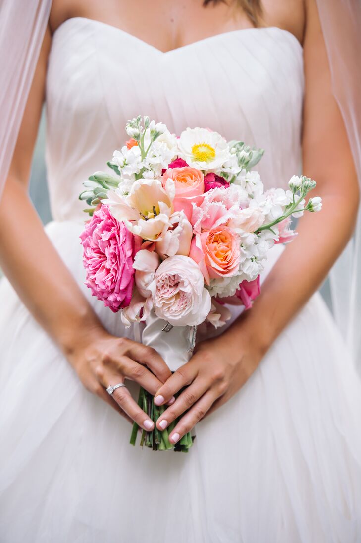 While Caroline's wedding dress and accessories were all ivory and silver, she added a pop of color with her bouquet. Events by Nouveau, their florist, filled its ivory satin wrap with blush and fuchsia garden roses, white delphiniums, peach roses and white tulips.