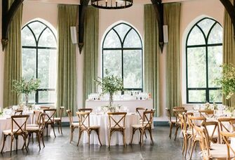 ballroom wedding venue with high ceilings, iron chandelier and green fabric drapes