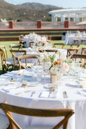 Round and Rustic Reception Tables With White Linens and Low Centerpieces on Lawn