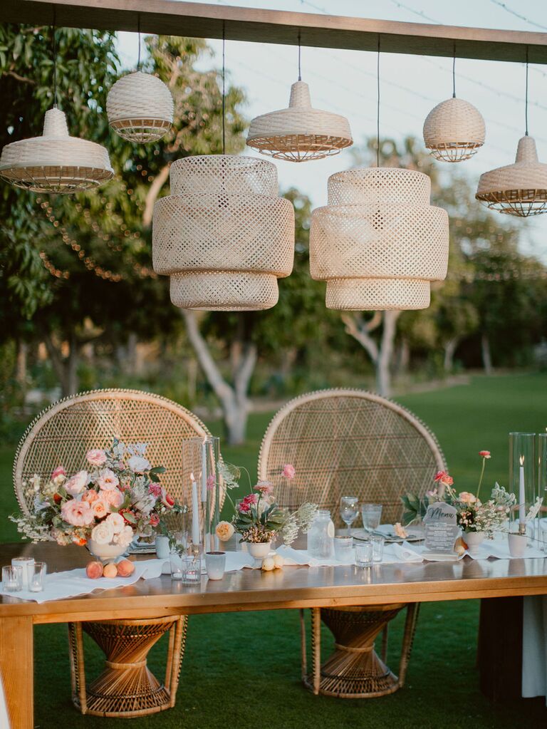 Boho sweetheart table with retro peacock chairs and rattan hanging lights