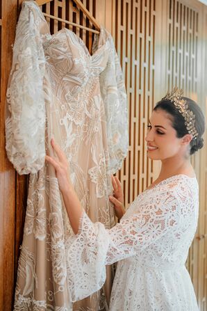 Bride in Gold Crown, Lace Robe Admiring Her Wedding Dress With Champagne Underlay on Hanger