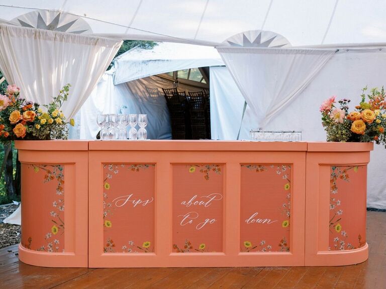 Floral and cursive personalized wedding bar at outdoor reception