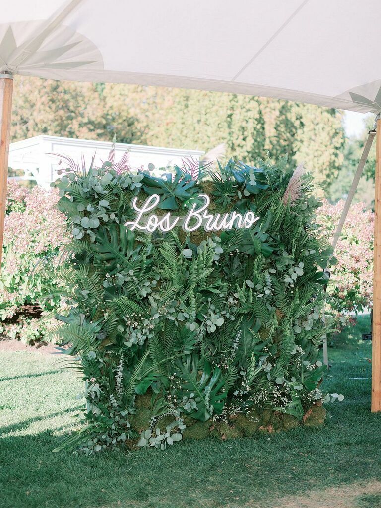 Greenery wall with custom neon sign inside sailcloth wedding tent