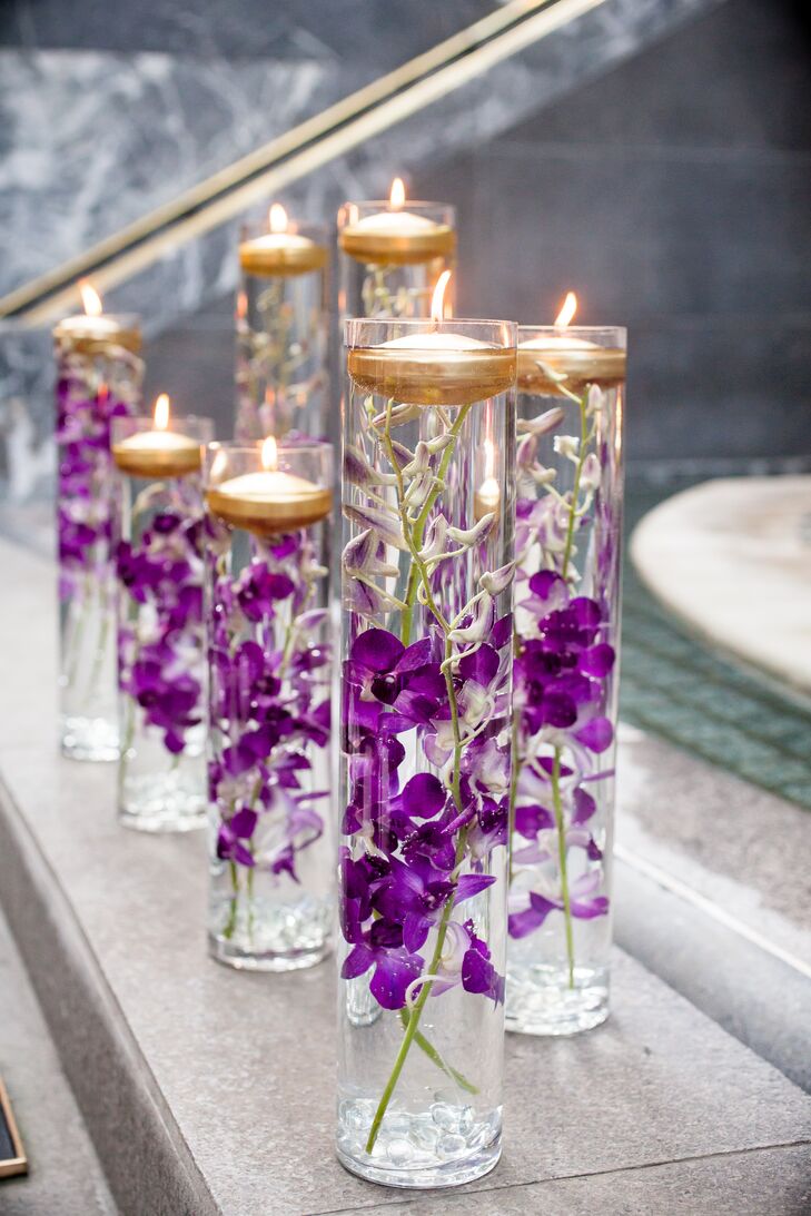 Glass vases were filled with purple orchids and floating gold candles for a romantic touch.