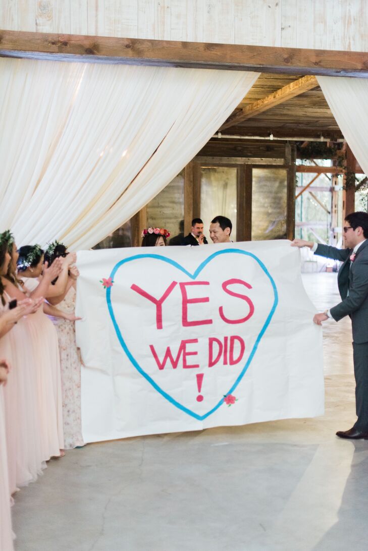 For their grand entrance, Deborah and Elton burst into their barn reception like champions, ripping through a paper banner that read “Yes, we did!”