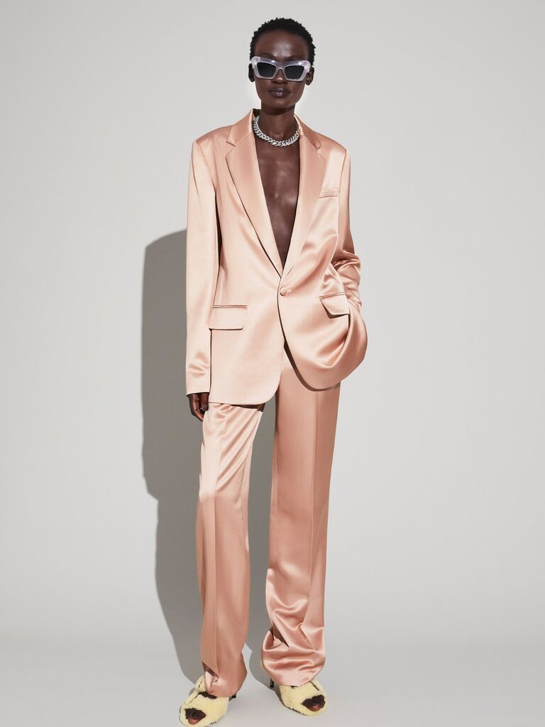 Model wears a trendy pink silk suit with a plunging neckline. 