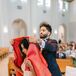 Groom in Dark Navy Tuxedo Kissing Bride With Long Veil on Forehead in Front of a Lake