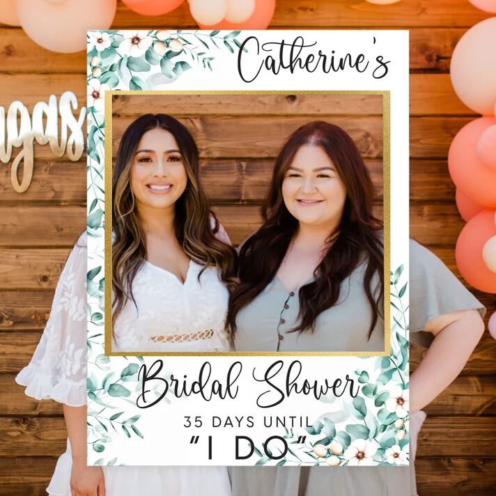 A couple stand in a fun bridal shower polaroid-inspired frame.