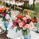 Vintage Blue Glassware and Bright Floral Arrangements on Wedding Reception Tables