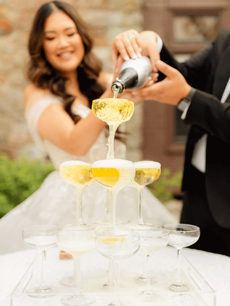 Bride and groom pour champagne for their Gatsby champagne tower. 