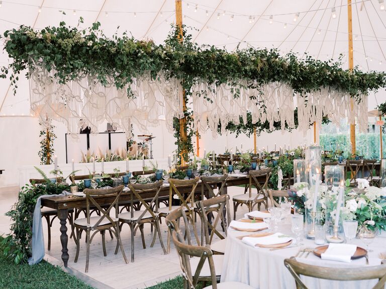 boho wedding reception tent with greenery garland and macrame ropes above long banquet table