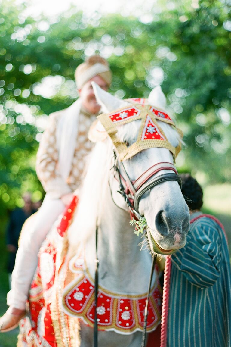 Groom on horse with red saddle for baraat