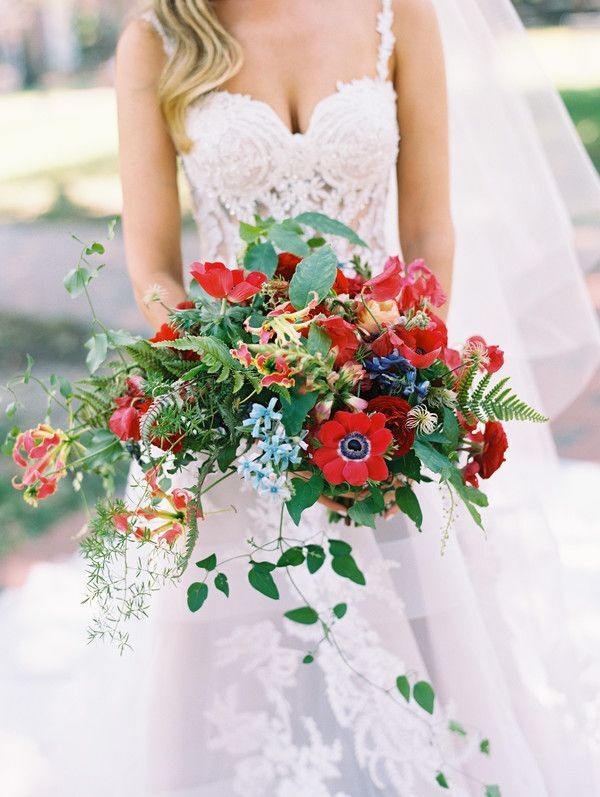 bride holding bouquet with red anemone blooms