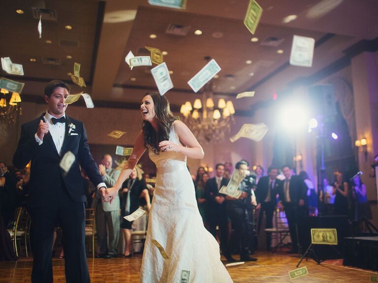 Couple laughs on the dance floor surrounded by dollar bills. 