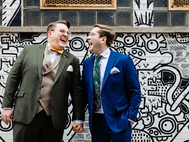 Couple laughs in front of a modern mural. 