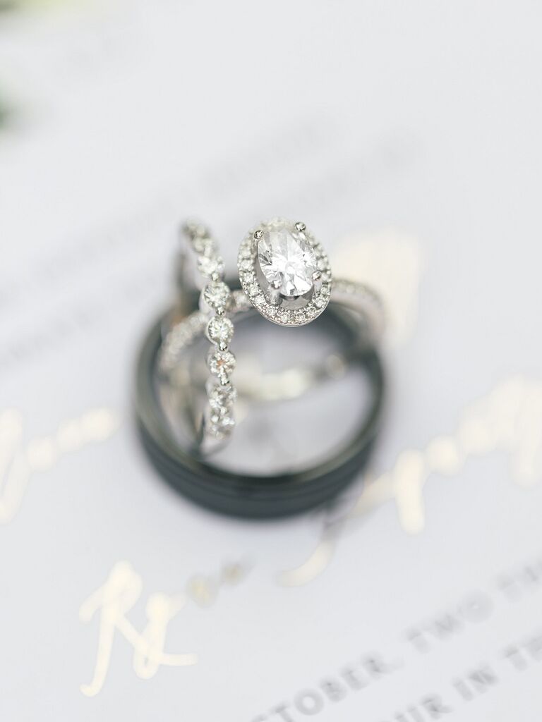 White gold oval-cut engagement ring stacked on two wedding bands