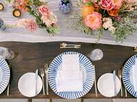 aerial photo of wedding tablescape with blue and white striped plates, ivory gauze table runner and centerpieces with pink and yellow flowers