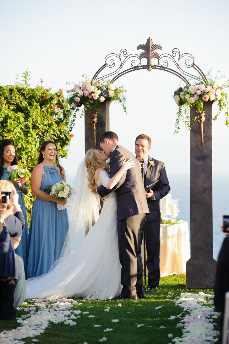 Jill and Peter shared their first kiss as a married couple during the outdoor ceremony at Trump National Golf Club in Rancho Palos Verdes, California. They kissed in front of the stone pillars with an iron arch that was accented in flower arrangements on top.