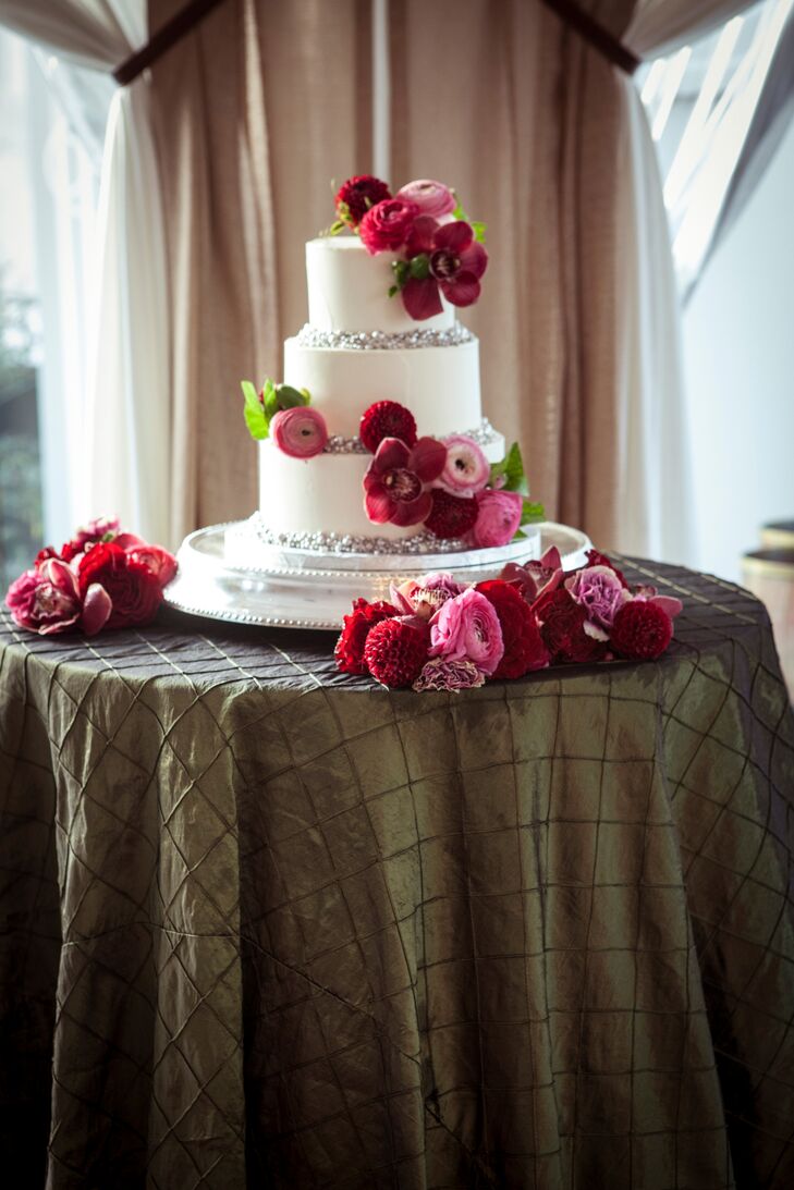 The couple’s lemon wedding cake with three-berry compote struck the perfect balance of glamour and romance in terms of design, with each buttercream-frosted layer boasting shimmery silvery accents and bright ranunculus, roses and dahlias in shades of red and pink.