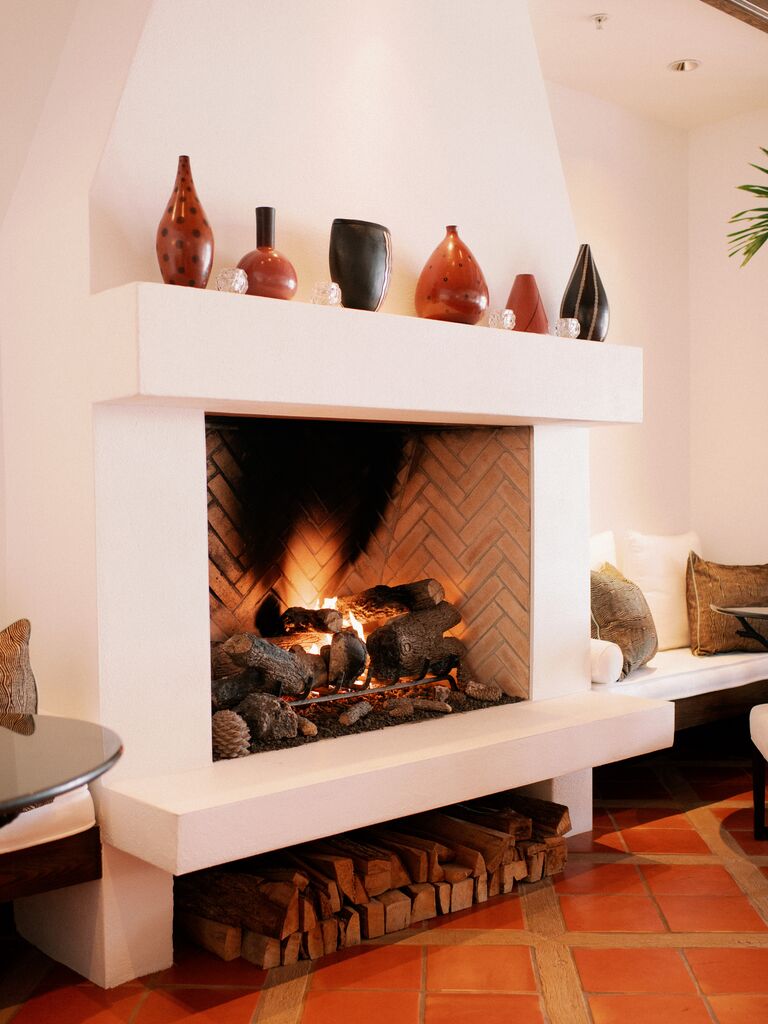 modern wedding fireplace decor idea with terracotta jars on top of large stucco hearth