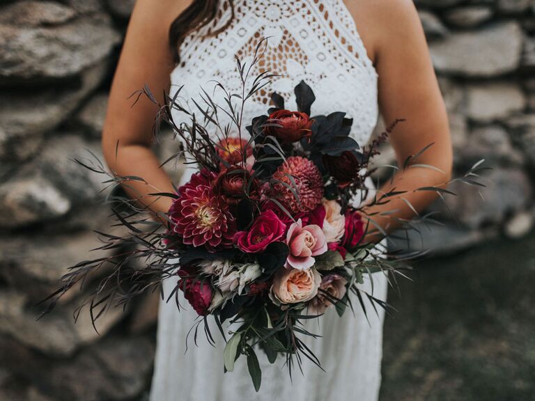 Bride holding moody dark purple fall wedding bouquet