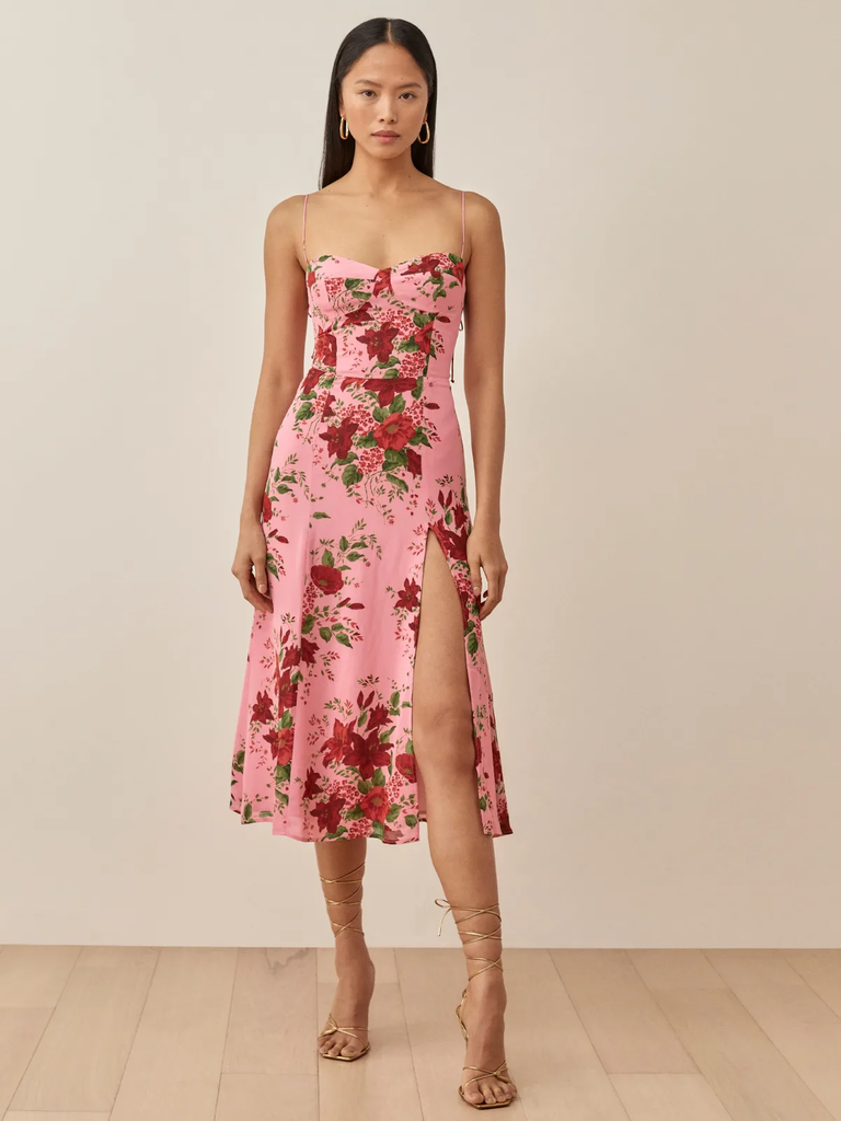 A model wears this spaghetti strap floral dress with a high slit.
