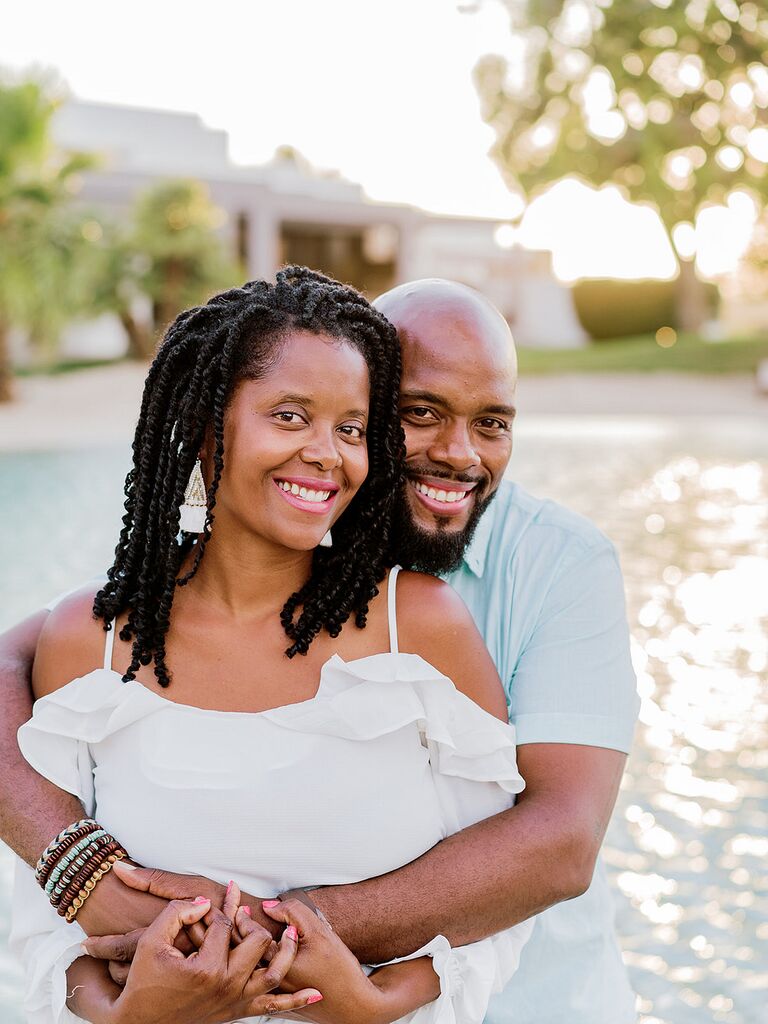 Couple shares hug during beach engagement photo shoot