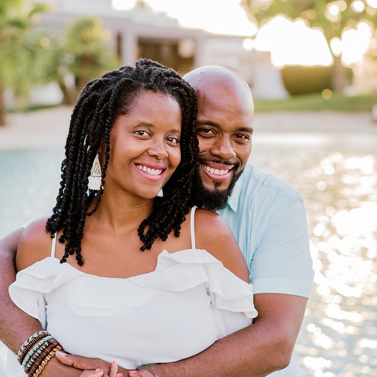 Couple shares hug during beach engagement photo shoot