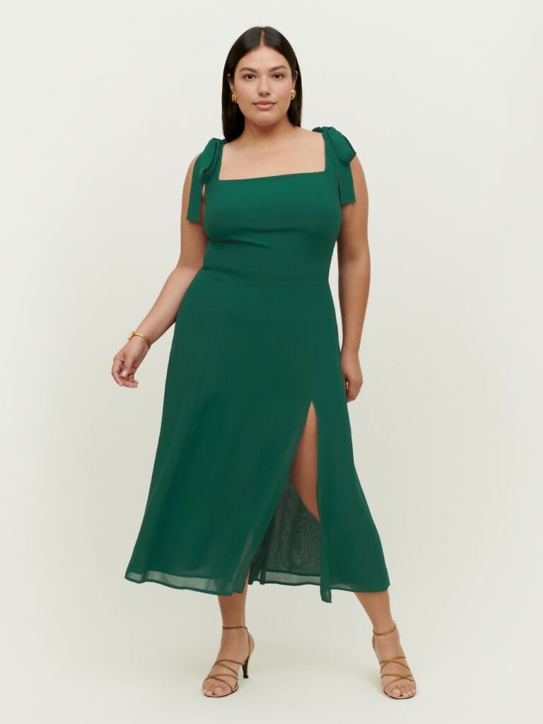 Model wears a green dress with tied sleeves. 
