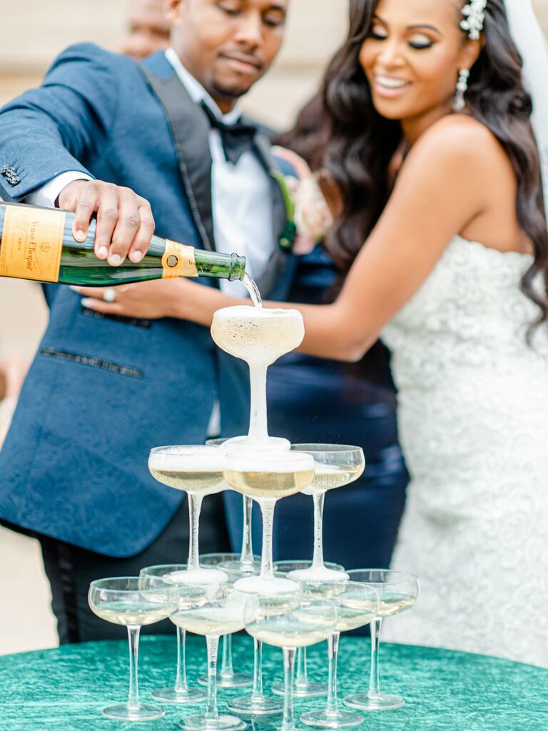 Bride and groom pouring champagne for a champagne tower. 