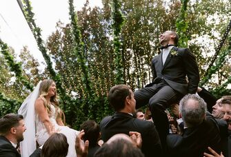 bride and groom being raised on chairs during Jewish hora dance