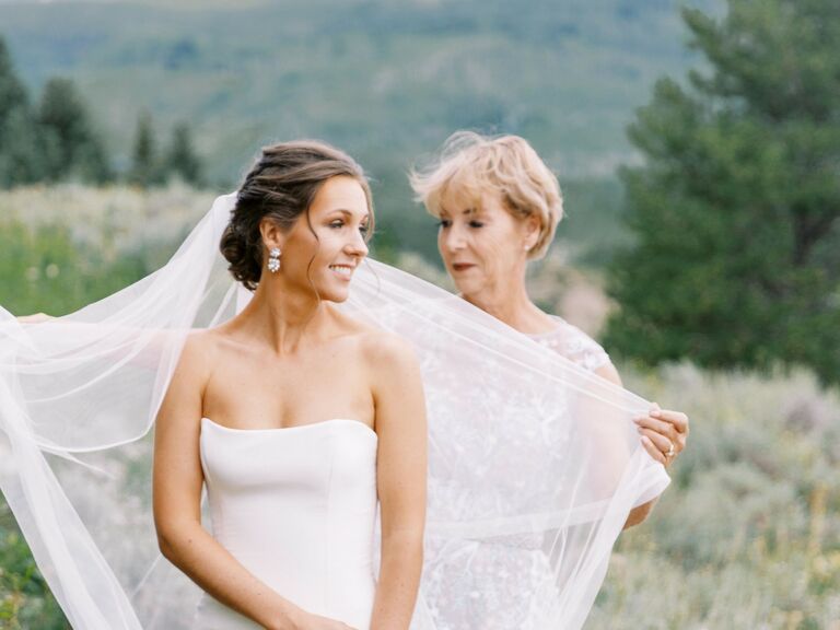 Mother adjusts the bride's veil at a beautiful mountainside wedding. 