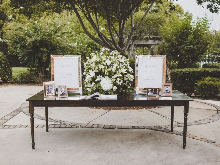 wedding gift table with large white lily centerpiece and childhood photos of the couple in silver frames