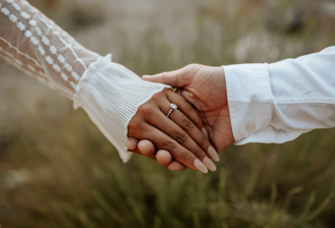 Couple holding hands with engagement ring on