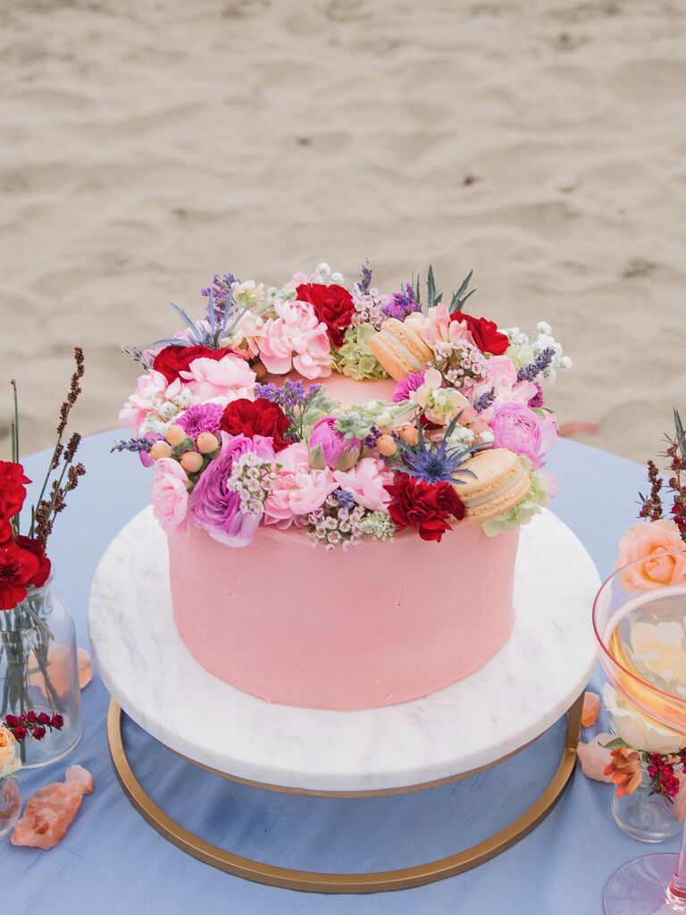 one tier pink wedding cake with halo of flowers and macarons on top