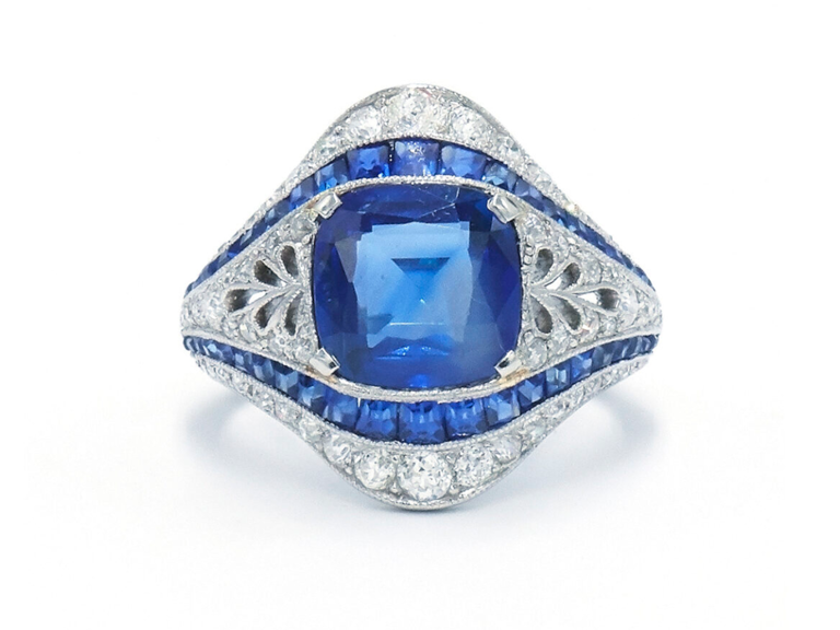 Center cushion sapphire stone set in thick silver band with smaller sapphire and diamond stones