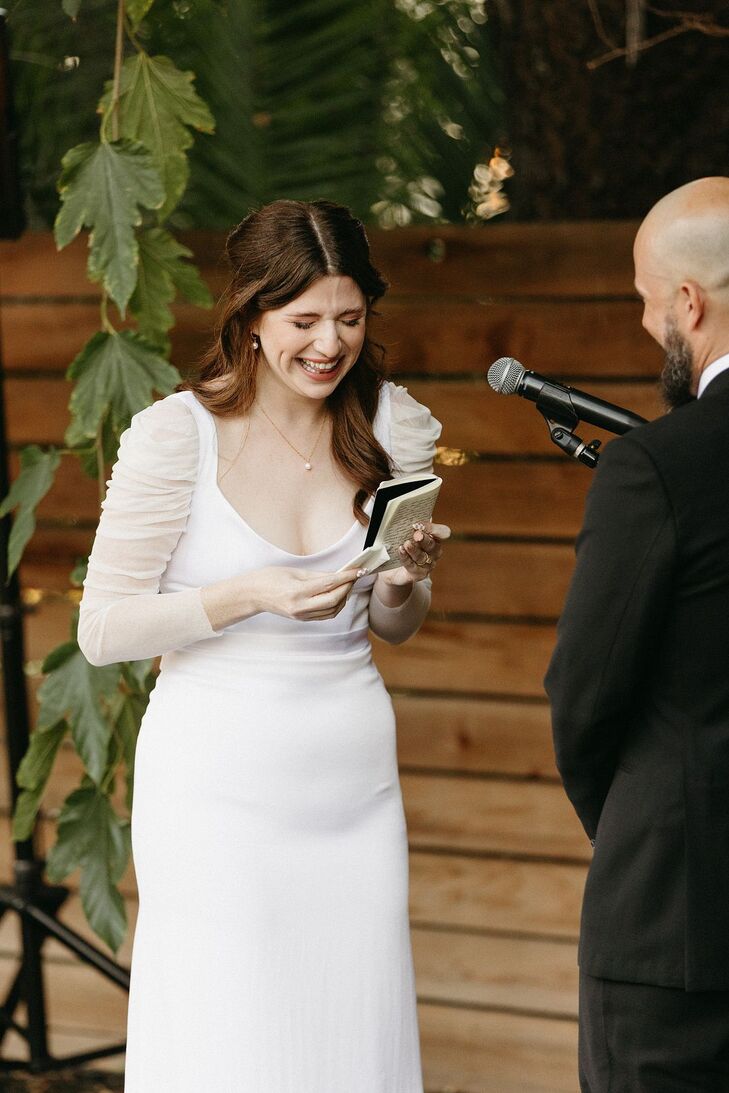 Bride in Modern Gown Getting Emotional Reading Vows From Book at Casual Ceremony