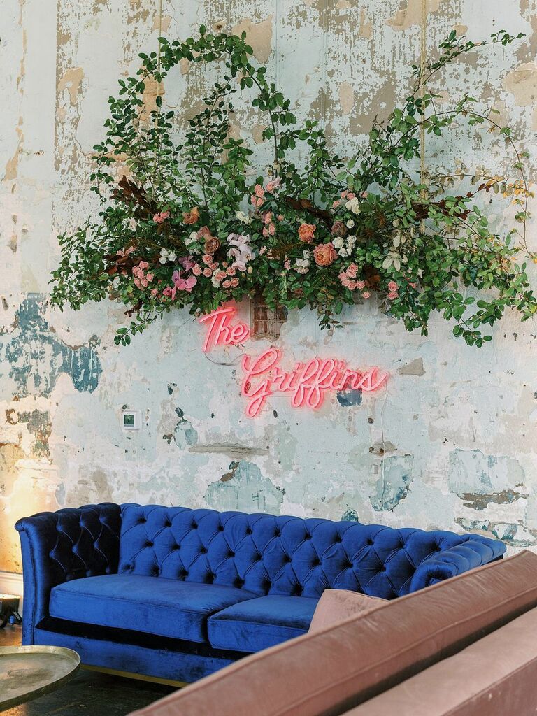 wedding cocktail lounge area with royal blue velvet sofa and pink neon sign that says "the griffins"