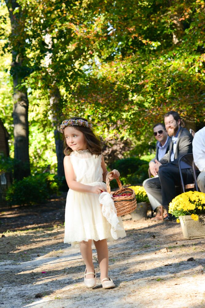 Stephanie and Michael’s daughter looked ready for a garden party during her processional. Her chic ivory chiffon dress had a lace trim along its pleated skirt and classic high neckline worthy of the Victorian era. She paired it with a colorful wildflower crown that matched Stephanie’s bouquet.