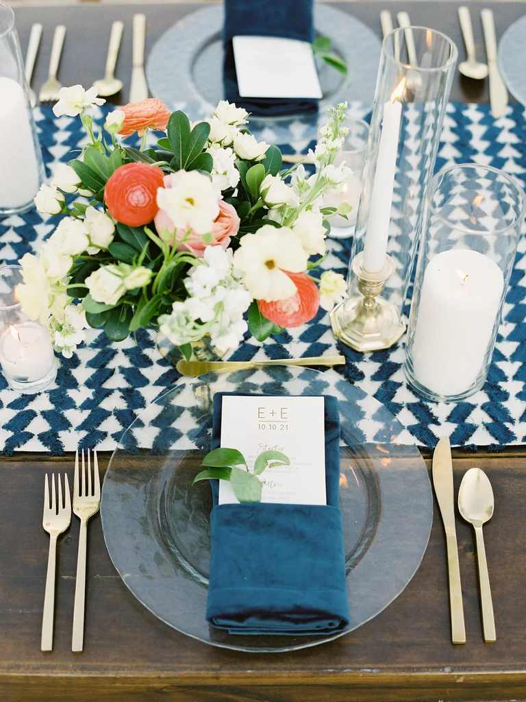A beautiful place setting in jewel-toned blue with a lovely floral arrangement in coral and white.